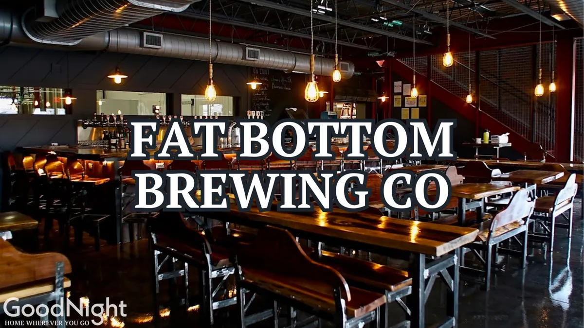 Inside a lively Nashville bar or eatery, long wooden tables and high-backed chairs invite groups of friends to gather. Pendant lights add warmth, and a bar area hints at craft beer tastings and live music nights.