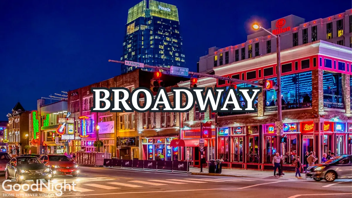 This energetic street scene features neon signs, bustling street traffic, people walking, and lively building facades aglow at night. The area exudes nightlife energy, with hints of dining, entertainment, and people-watching.